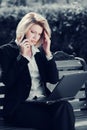 Young business woman with laptop calling on cell phone