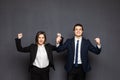 Young business woman and man showing winner gesture isolated over gray background Royalty Free Stock Photo