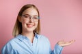 Young business woman or manager in glasses office clothes smiles show side gesture by hand. Teenage girl student wearing