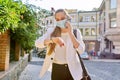 Young business woman in medical protective mask talking on smartphone, looking at wristwatch Royalty Free Stock Photo