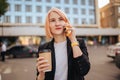 Young business woman with mobile phone device and a eco paper made cup of coffee outdoors Royalty Free Stock Photo