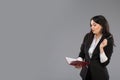 Young business woman with notepad and pen close to her chin. Pensive business lady writing on clipboard standing over Royalty Free Stock Photo