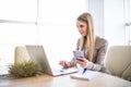 Young business woman with phone in hand using laptop at office Royalty Free Stock Photo