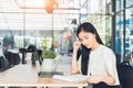 Young business woman reading a report her hand holding a pen sitting in a coffee shop Royalty Free Stock Photo