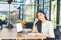 Young business woman reading a report her hand holding a pen sitting in a coffee shop Royalty Free Stock Photo