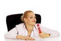 Young business woman sitting behind the desk and holding big pen Royalty Free Stock Photo