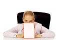 Young business woman sitting behind the desk and holding a board with ban Royalty Free Stock Photo