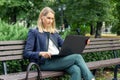 young business woman sitting on the bench in the city park and using laptop. outdoor office Royalty Free Stock Photo