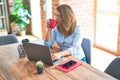 Young business woman sitting at desk working using computer laptop, drinking a cup of coffee at the office Royalty Free Stock Photo