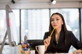 Young business woman sitting in the office is thinking about idea in front of a laptop computer looking up and  and holding pencil Royalty Free Stock Photo