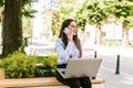 Young business woman sitting outdoor talking on phone while working on laptop Royalty Free Stock Photo