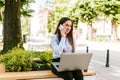 Young business woman sitting outdoor talking on phone while working on laptop Royalty Free Stock Photo