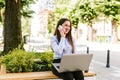 Young business woman sitting outdoor talking on phone while working on laptop Royalty Free Stock Photo