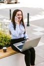 Young business woman sitting outdoor talking on phone while working on laptop Royalty Free Stock Photo