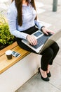 Young business woman sitting outdoor talking on phone while working on laptop Royalty Free Stock Photo