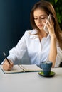 Young business woman sitting at table in cafe, talking on cell phone while taking notes in notebook. woman freelancer Royalty Free Stock Photo