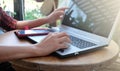 Young business woman sitting on wooden table at the coffee cafe and using modern laptop working and her finger is pointing at the Royalty Free Stock Photo