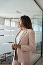 Young business woman standing in office looking away thinking, vertical. Royalty Free Stock Photo