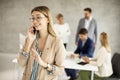 Young business woman standing in the office and suing mobile phone in front of her team Royalty Free Stock Photo