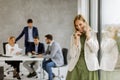 Young business woman standing in the office and using mobile phone in front of her team Royalty Free Stock Photo