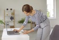 Young business woman standing by office work desk and using laptop and mobile phone Royalty Free Stock Photo