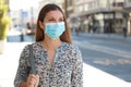 Young business woman with surgical mask waiting bus on bus stop in city street Royalty Free Stock Photo