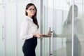 Young business woman with tablet computer opening glass office door Royalty Free Stock Photo
