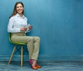 Young business woman with tablet sitting on chair.
