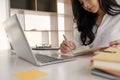 Young business woman taking notes in notebook.On table is laptop for online learning or business finance concept Royalty Free Stock Photo