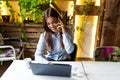 Young business woman using her laptop at a cafe. Beautiful woman sitting at a table with a cup of coffee and mobile phone surfing Royalty Free Stock Photo