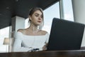 Young business woman using laptop computer in cafe or in coworking. Blond female working on laptop in an outdoor cafe. Royalty Free Stock Photo