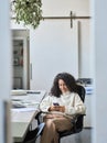 Young business woman using mobile working in office sitting at desk, vertical. Royalty Free Stock Photo