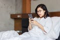 Young business woman using moble phone on bed while working from home during covid -19 crisis