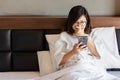 Young business woman using moble phone on bed while working from home during covid -19 crisis