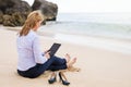 Business woman using tablet computer while sitting on the beach Royalty Free Stock Photo