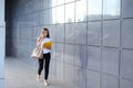 Young business woman walks and talks on phone, holds documents and smiling on background of wall of business center. Royalty Free Stock Photo