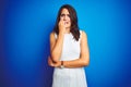 Young business woman wearing white elegant dress standing over blue isolated background looking stressed and nervous with hands on Royalty Free Stock Photo