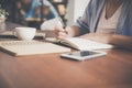 Young business woman in white dress sitting at table in cafe and writing in notebook. Asian woman talking smartphone. Royalty Free Stock Photo