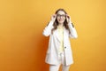 young business woman in white suit and blazer puts on glasses on orange isolated background