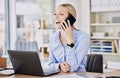 Young business woman working in modern office, making phone call while sitting in front of her laptop. Female Royalty Free Stock Photo