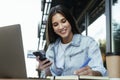 Young business woman working on open terrace home, sitting in front of laptop, taking notes in black notebook.