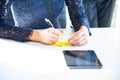 Young business woman is working, writing on the paper or notepad and meeting with the co-worker in the office about the future of Royalty Free Stock Photo