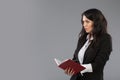 Young business woman writing down notes to notepad. Pretty thoughtful business lady writing on clipboard standing over Royalty Free Stock Photo