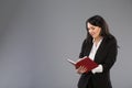 Young business woman writing down notes to notepad. Pretty thoughtful business lady writing on clipboard standing over Royalty Free Stock Photo