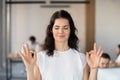 Young business woman employee meditating in office with eyes closed Royalty Free Stock Photo