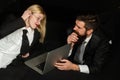 Young business woman and handsome businessman in suits are using a laptop in black. Boss and secretary.