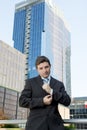 Young businessman adjusting shirt cuff link outdoors at exterior office building