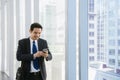 Young businessman in airport. Casual urban professional business man using smartphone smiling happy inside office building. Royalty Free Stock Photo