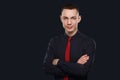 Young businessman with arms crossed standing over dark background. Studio shot Royalty Free Stock Photo