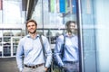 A young businessman with a bag walking in front of a modern building. Royalty Free Stock Photo